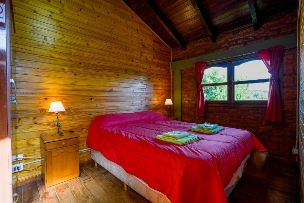 1 dormitorio con 1 cama roja en una cabaña de madera en Brisas del Sur, en El Bolsón