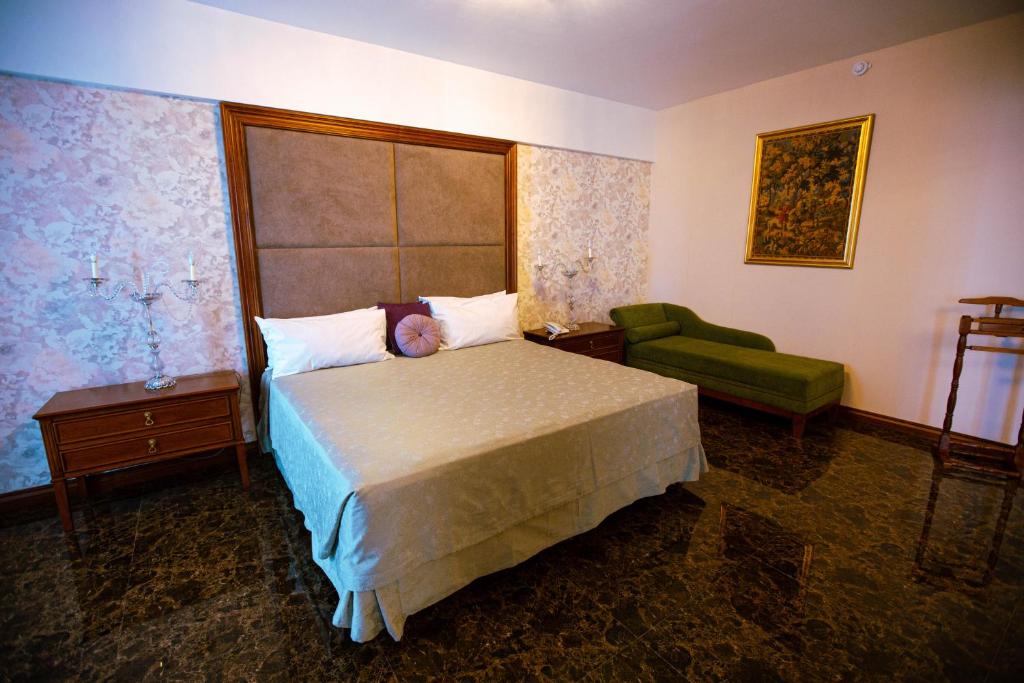 a bedroom with a bed and a green chair at El Aguila del Tuyu in San Clemente del Tuyú