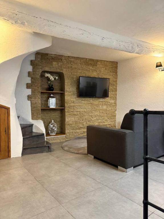 un salon avec une télévision sur un mur en briques dans l'établissement Maison de village St Paul de Vence, à Saint-Paul-de-Vence