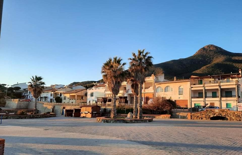a parking lot with palm trees and a building at Domu Asquer 9 in Fluminimaggiore