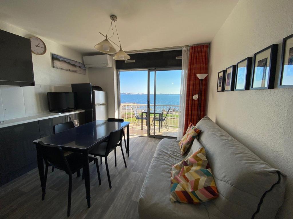 un salon avec un canapé et une table avec vue dans l'établissement Appartement 2 étoiles climatisé avec balcon, proche Thermes, animaux admis - FR-1-503-37, à Balaruc-les-Bains