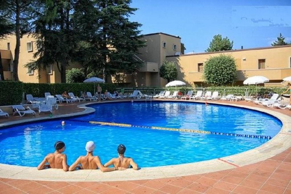 ペスキエーラ・デル・ガルダにあるAppartamenti Massimilianoの三人の少年がスイミングプールに座っている