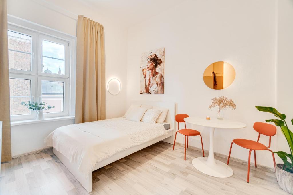 オポーレにあるCOMFISTAY Rynek 32A - Apartament na Starym Mieścieの白いベッドルーム(ベッド1台、テーブル付)