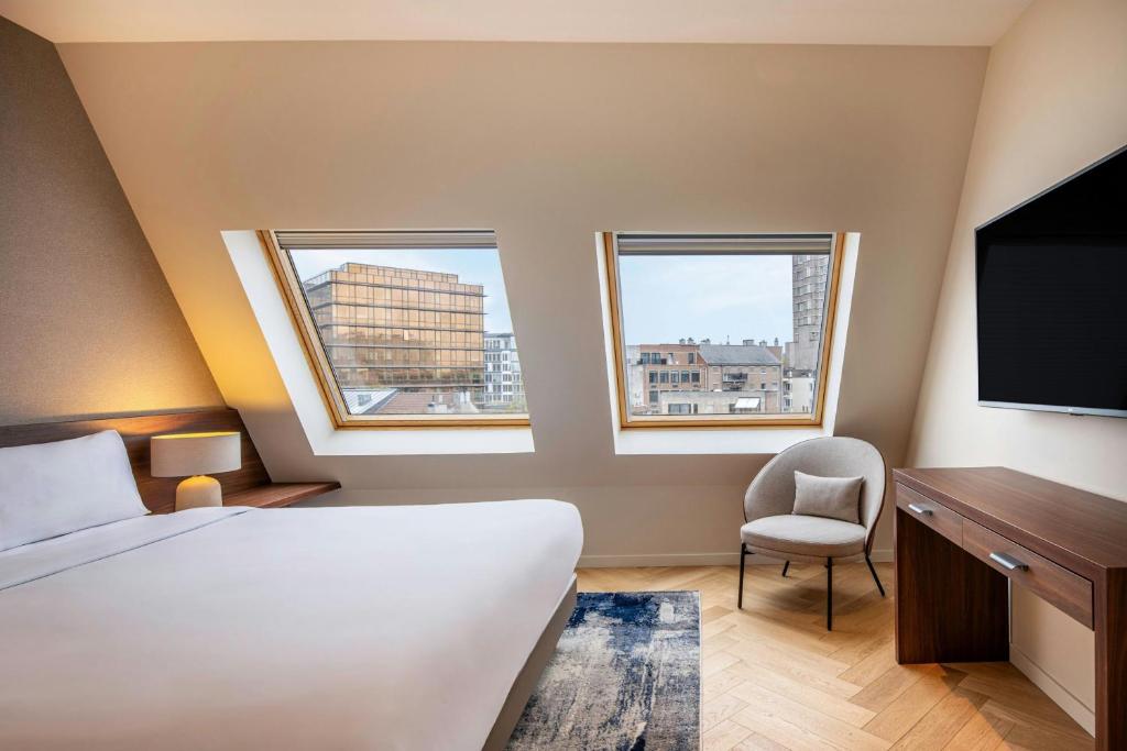 a hotel room with a bed and a tv and two windows at Marriott Executive Apartments Brussels in Brussels
