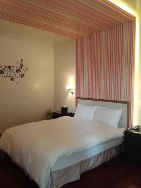 a bedroom with a large white bed with a striped wall at Cocos Hot Spring Hotel in Ruisui