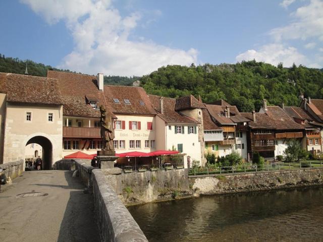 un gruppo di edifici vicino a un fiume di Hostel Le Chandelier a Saint-Ursanne