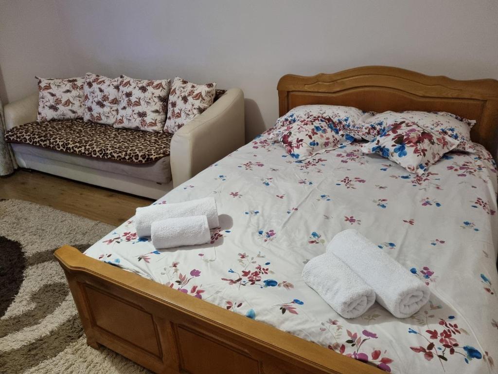 ein Bett mit Handtüchern und ein Sofa in einem Schlafzimmer in der Unterkunft Garsoniera Emilia in Câmpulung Moldovenesc