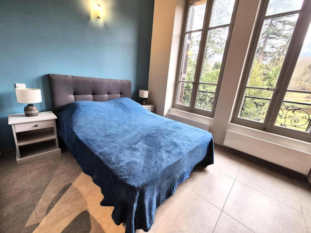 une chambre avec un lit bleu et deux fenêtres dans l'établissement Résidence Le Bernascon - Cosy studio proche d'un agréable Parc 