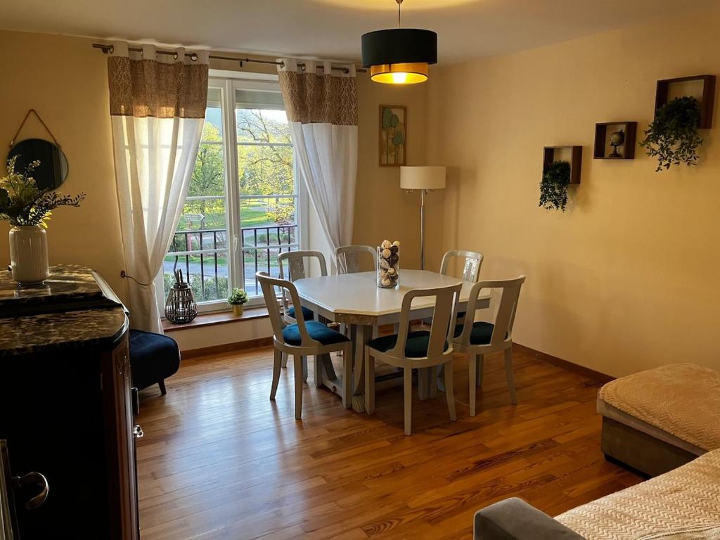 une salle à manger avec une table et des chaises blanches dans l'établissement Au pied du Lac, à Gérardmer