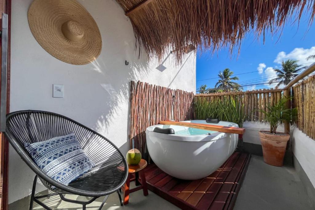 y baño con bañera y silla en el patio. en Nomad Palmeira Duplex com Hidromassagem privativa, en Porto de Pedras