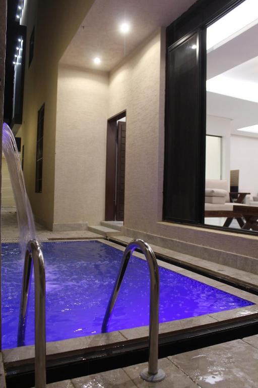a swimming pool with two chairs in a hotel room at فيلا مكونة من 3 غرف نوم و مجلس و صالة و مطبخ وغرفة عاملة و مسبح تفتح الغرف حسب عدد النزلاء in Riyadh