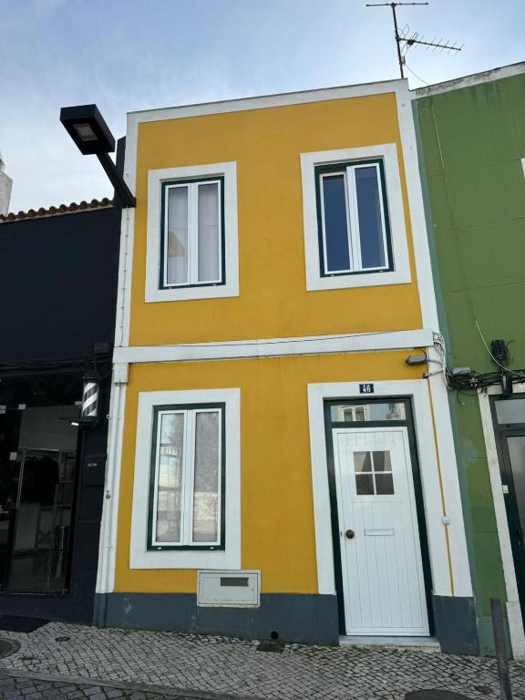 a yellow and green house with a white door at Moradia aconchegante in Póvoa de Santa Iria
