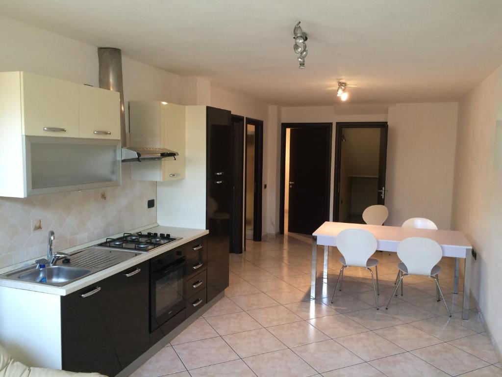 a kitchen with a sink and a table with chairs at Comfort Apartment in Assemini