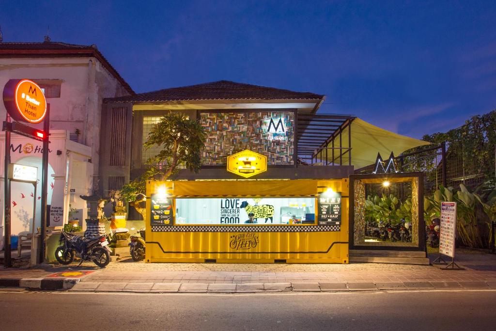 a yellow store with a sign on the side of a street at M Boutique Hostel in Seminyak