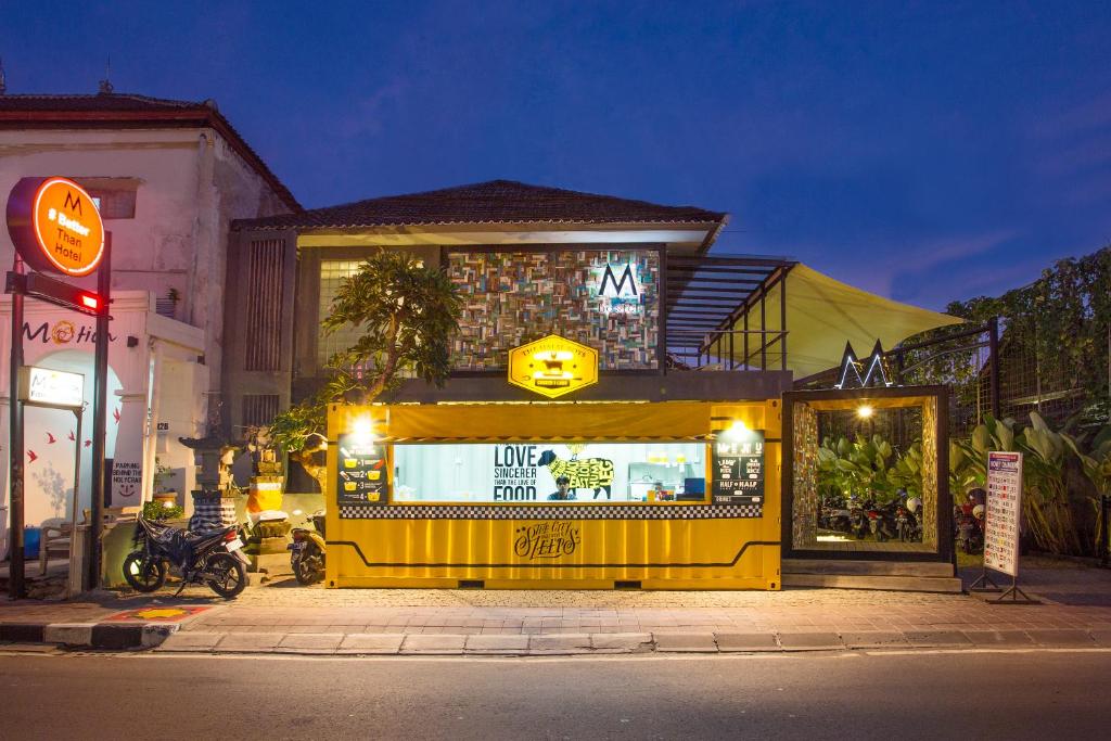 un negozio giallo con un cartello sul lato di una strada di M Boutique Hostel a Seminyak