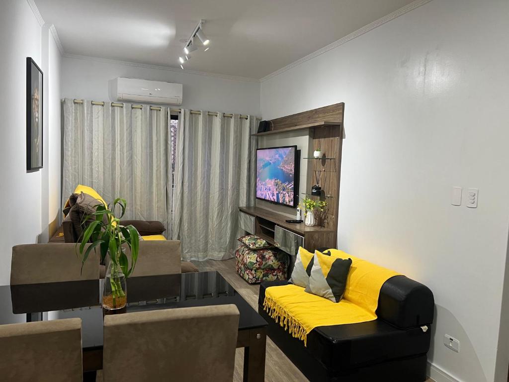a living room with a couch and a tv at Aconchego no Canto do Forte - Ar Condicionados - Tvs Grandes - Wi-fi e Estacionamento Incluso! in Praia Grande