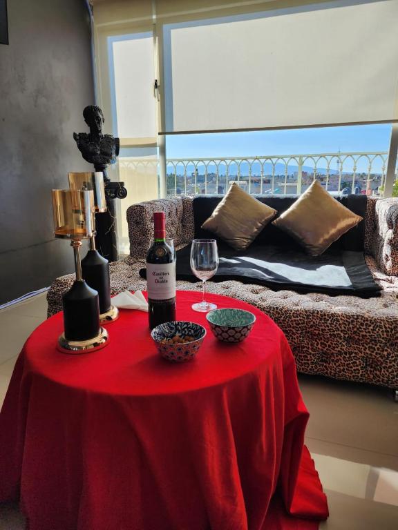 a red table with wine bottles and glasses on it at SUITES LIVE Toluca in Toluca