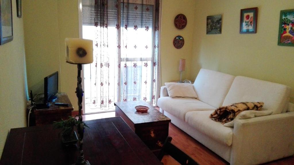 uma sala de estar com um sofá branco em frente a uma janela em Apartamento Anaper em Málaga