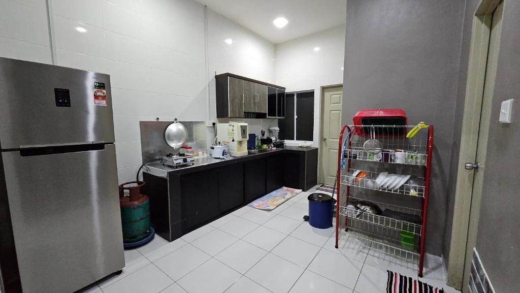 a kitchen with a counter and a refrigerator in it at Mem's Homestay Haziiq Jaya in Kuching