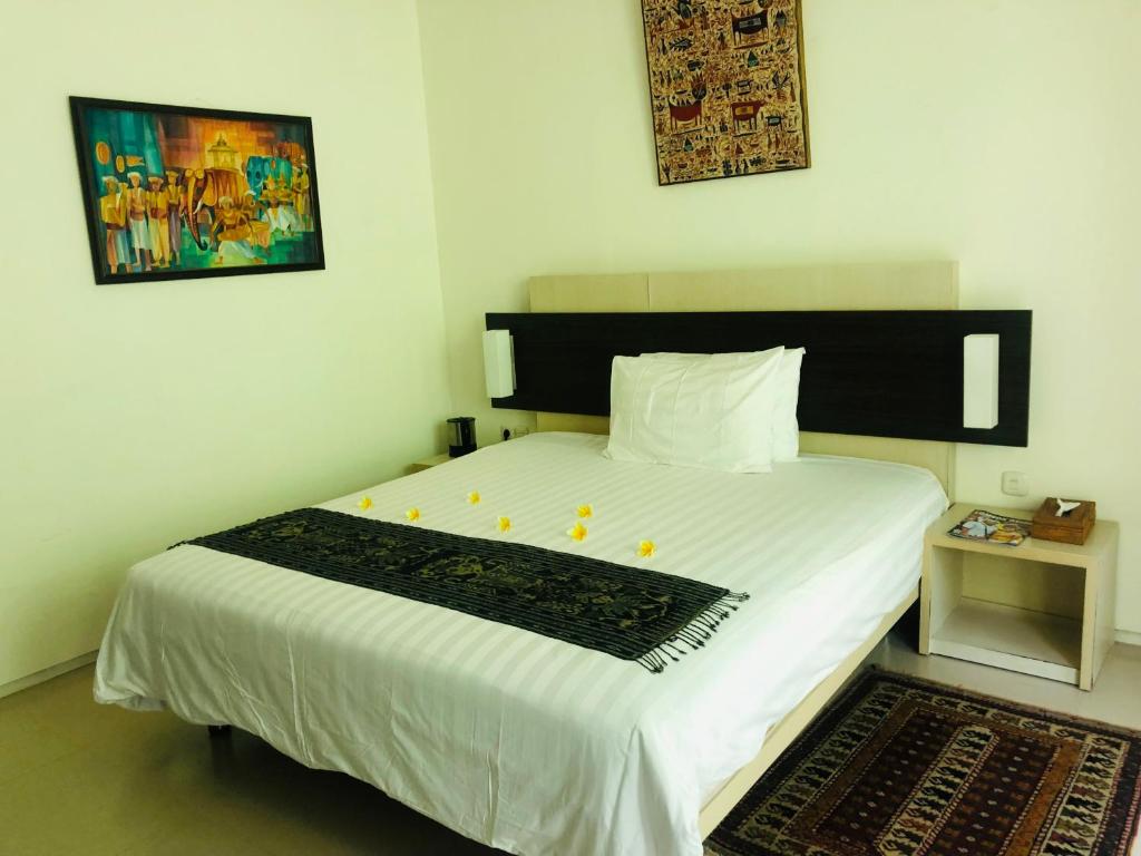 a bedroom with a white bed with a black headboard at Villa Karingal in Senggigi