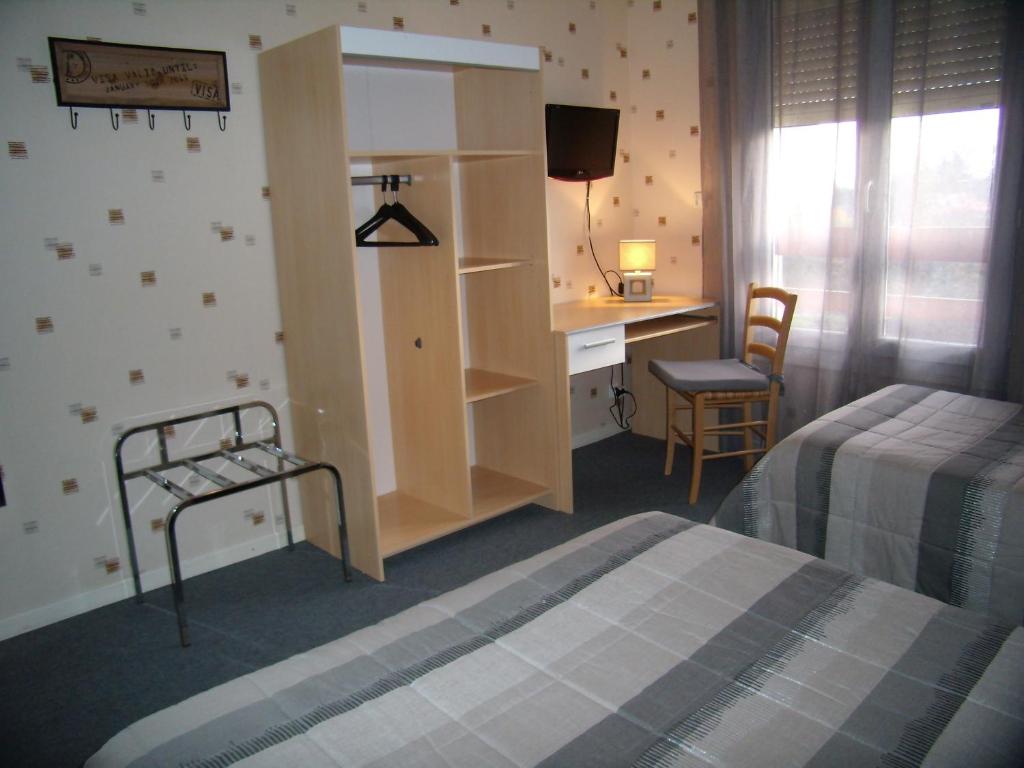 a hotel room with a bed and a desk and a bedroom at Hôtel Le Relais in Fleurance