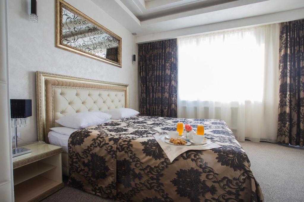 Una habitación de hotel con una cama con una bandeja de comida. en Отель Ринг Премиум, en Volgograd