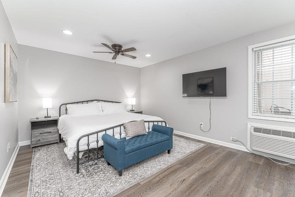 a white bedroom with a bed and a blue chair at Downtown Kimmswick Studio-Renovated-Prime Location in Imperial