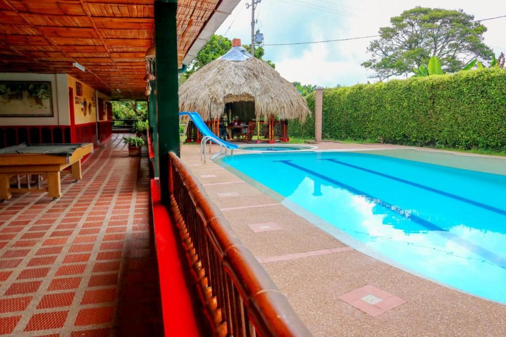 a swimming pool with a slide next to a house at Finca Hotel La Paloma in Quimbaya