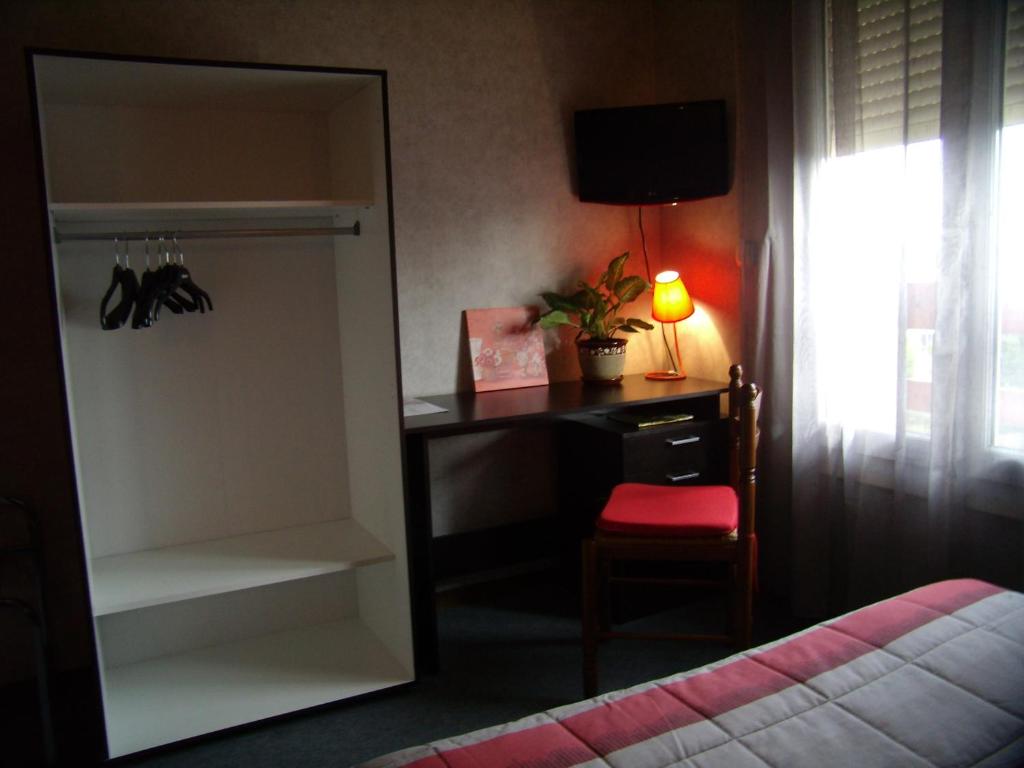 a bedroom with a desk and a bed and a window at Hôtel Le Relais in Fleurance