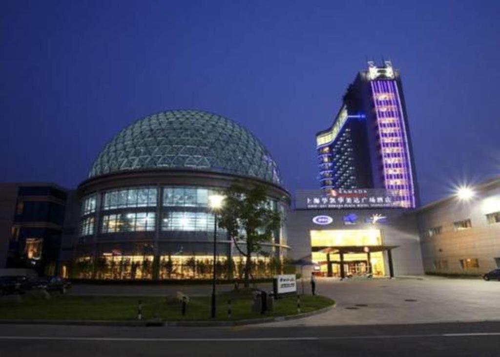 a large glass building with a tall building in the background at Ramada Plaza Sino-Bay Shanghai in Fengxian