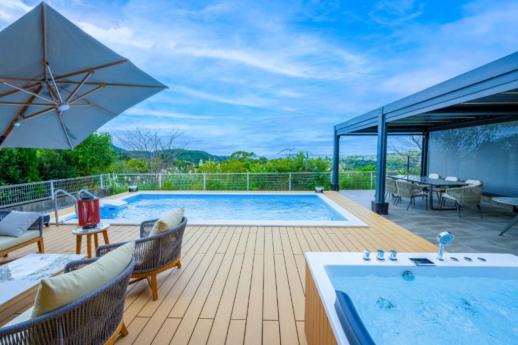 a swimming pool on a wooden deck with an umbrella at Villa MILA MOTOBU in Motobu