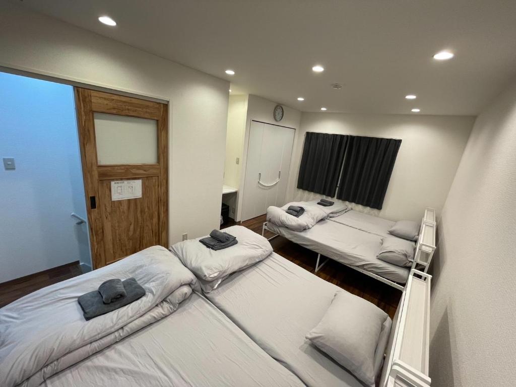 a room with three beds in it with a window at LAINA Kyobashi in Osaka