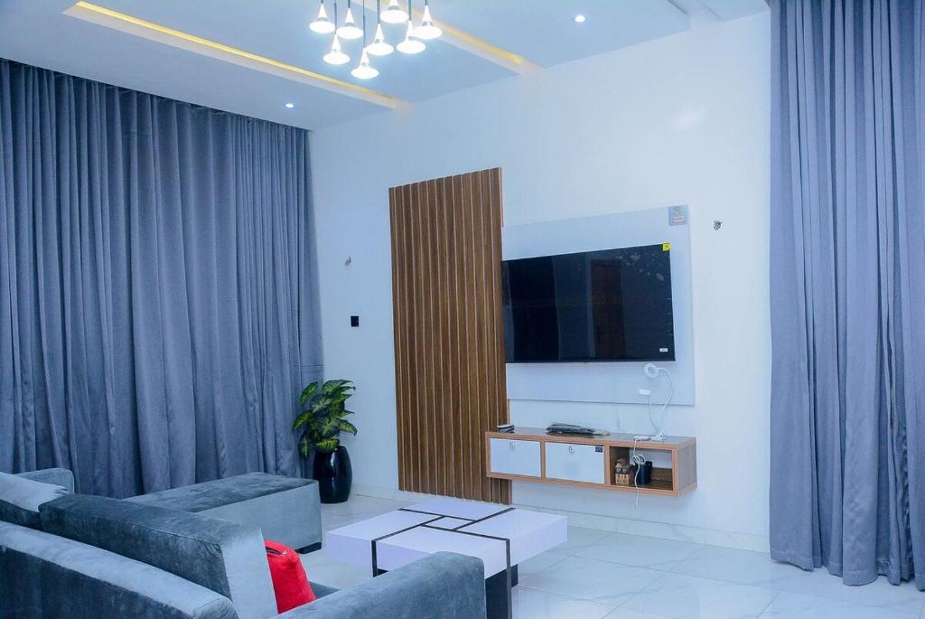a living room with a couch and a flat screen tv at Stylish Haven, Luxe & Cozy in Mama