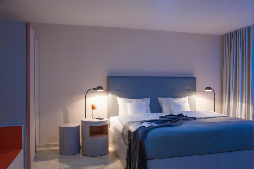 um quarto com uma cama com uma colcha azul e 2 candeeiros em The Grey Design Hotel em Dortmund
