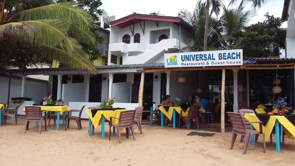 a restaurant with tables and chairs on the beach at Hotel Universal Beach in Hikkaduwa