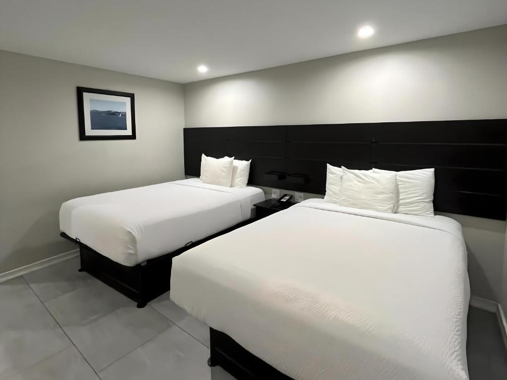 two beds in a hotel room with white sheets at Inn By the Bay Monterey in Monterey