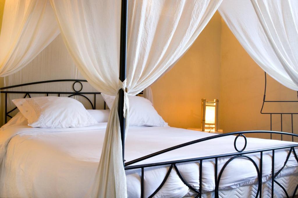 サン・テティエンヌ・ド・バイゴリにあるChambres d'Hôtes Jauregiaのベッドルーム1室(白いシーツとカーテン付きのベッド1台付)