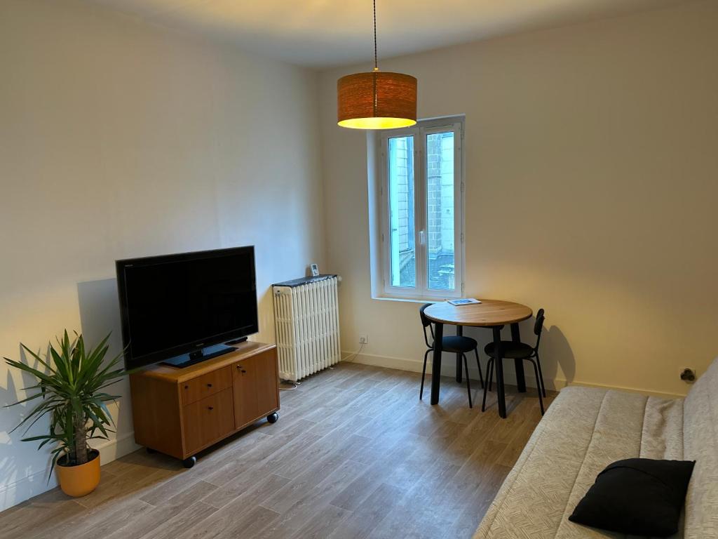 un salon avec une télévision à écran plat et une table dans l'établissement Quiet T2 Downtown overlooking Saumur Castle, à Saumur