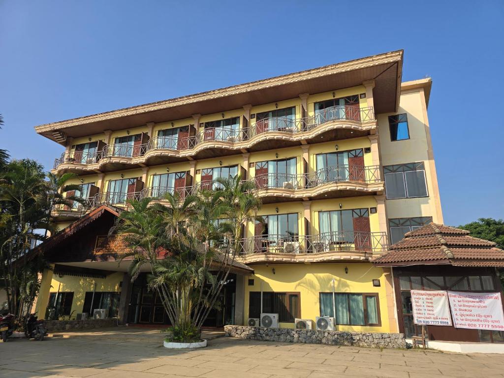 a building with a palm tree in front of it at Thavisouk Hotel, Vang Vieng in Vang Vieng
