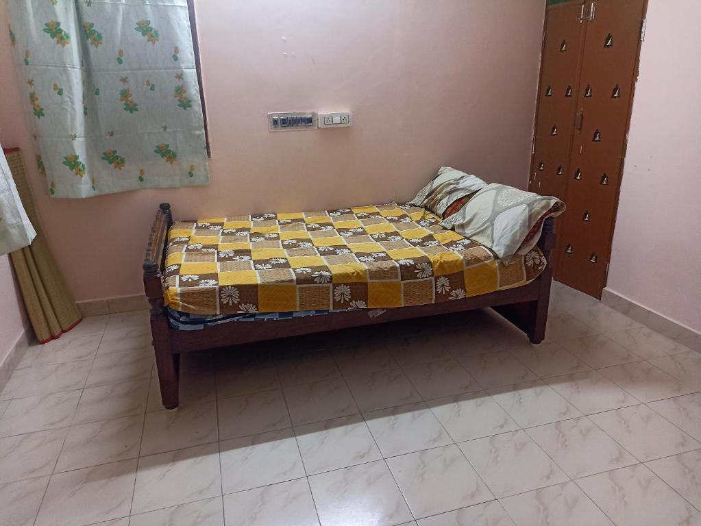 un piccolo letto in una camera con un giallo e un marrone di OM Arunachalam Home Stay a Tiruvannāmalai