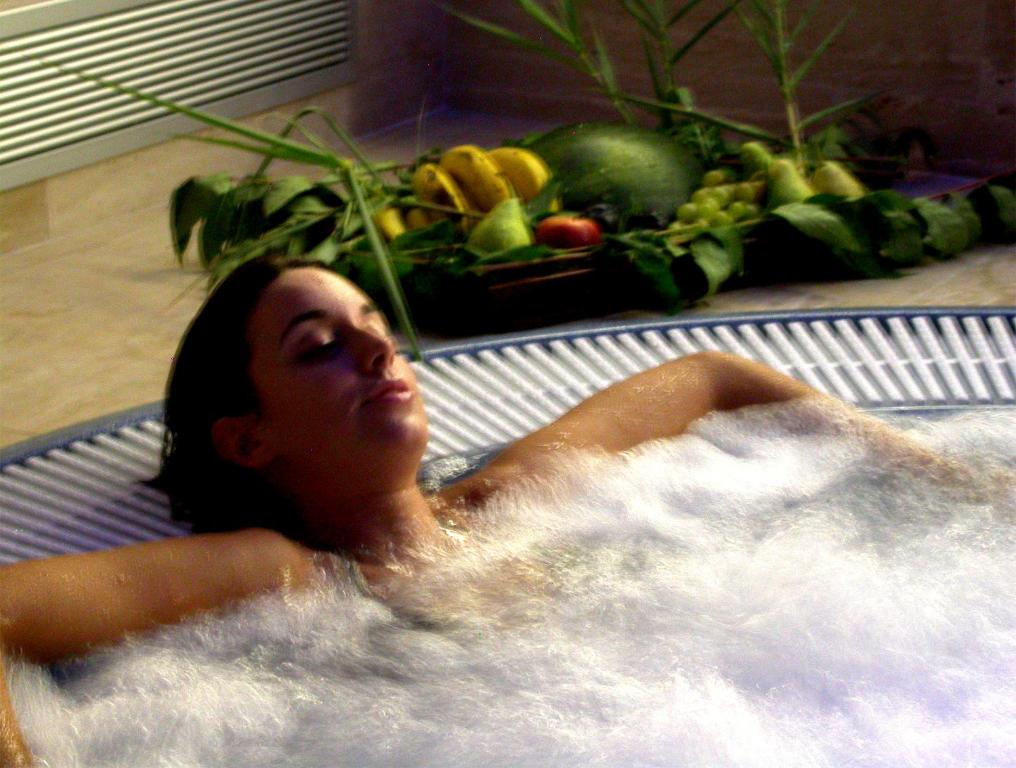 Una mujer tumbada en una bañera con verduras. en Hotel Hyltor, en Archena