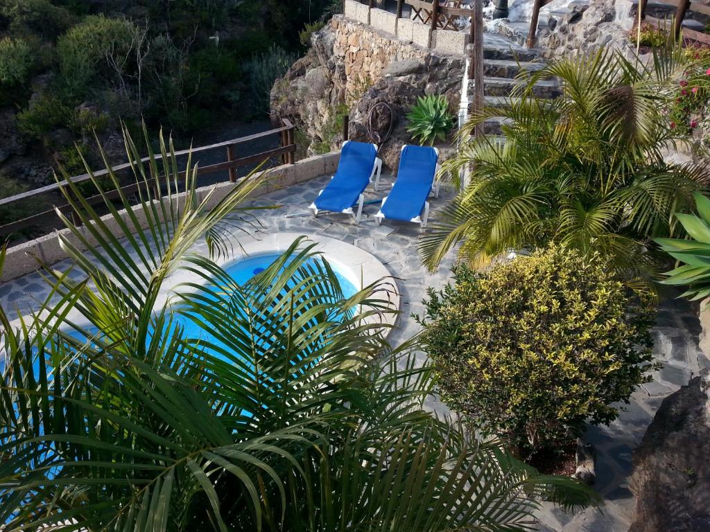 two blue chairs in a swimming pool with palm trees at Casa Rural La Cuadra in Las Vegas