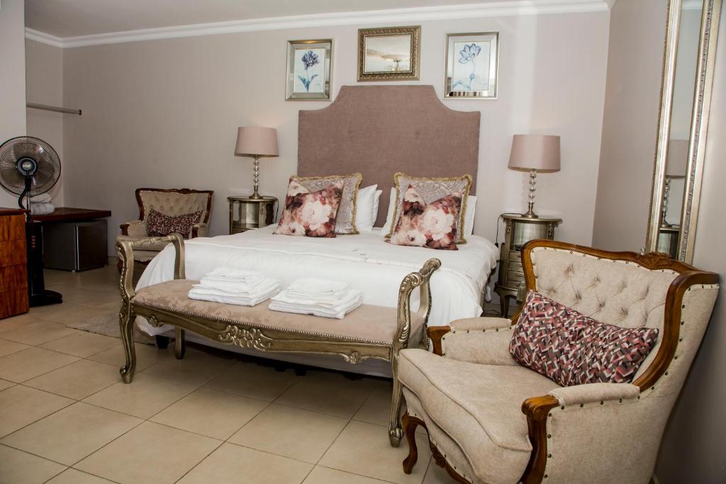 a bedroom with a bed and two chairs at La Vida Luka - Luxury Guesthouse in Pretoria