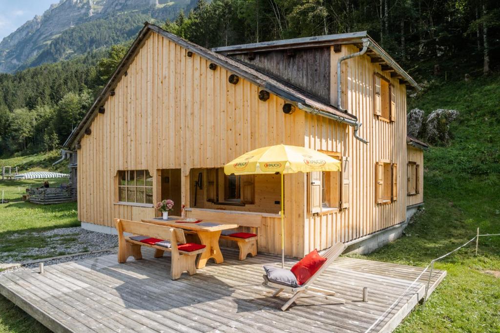 a house with a wooden deck with a table and an umbrella at Alp Hütte Bregenzerwald in Schnepfau