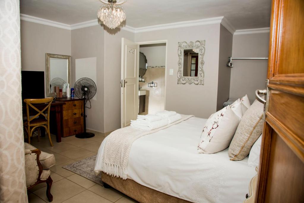 a bedroom with a bed and a desk and a mirror at La Vida Luka - Luxury Guesthouse in Pretoria
