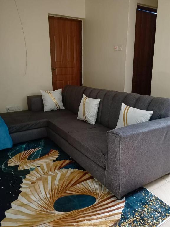 a gray couch in a living room with a rug at Bnb kamakis in Ruiru