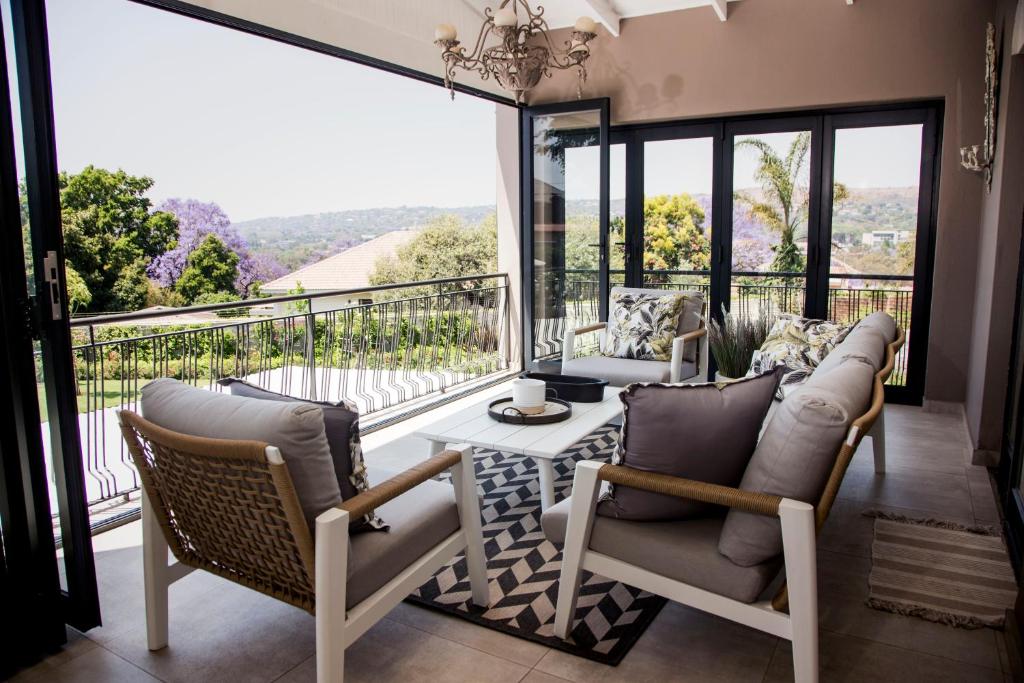 a living room with a table and chairs on a balcony at La Vida Luka - Luxury Guesthouse in Pretoria
