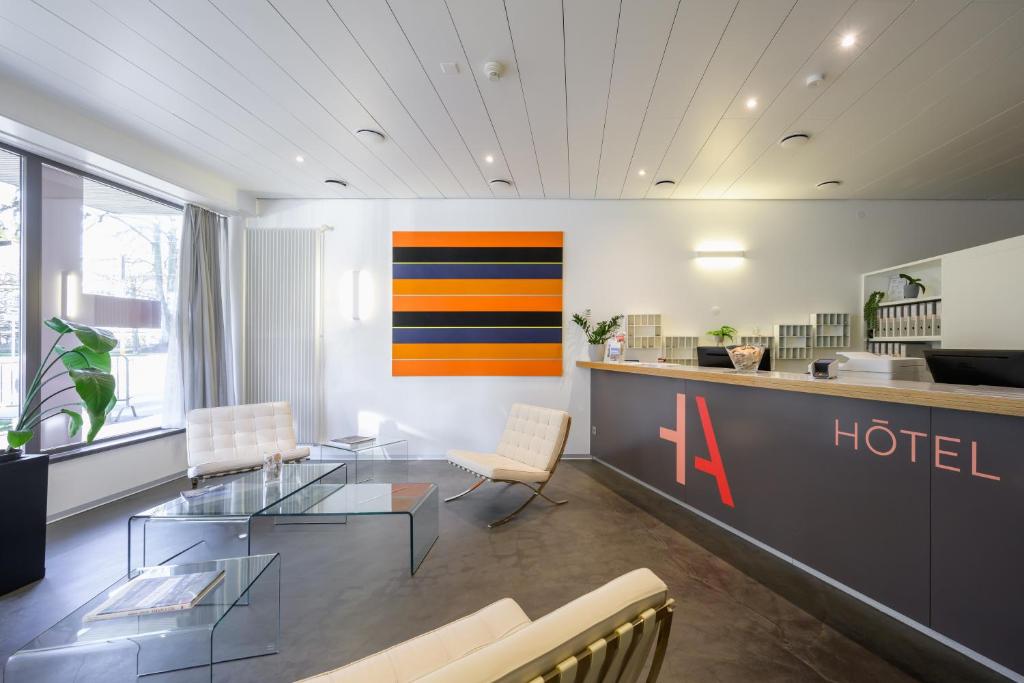 un vestíbulo con mesa de cristal y sillas en Hôtel Des Arts, en Neuchâtel