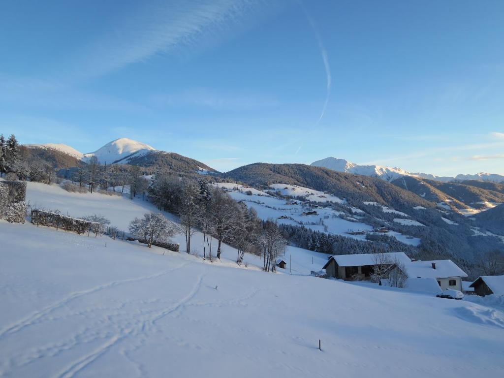 a snow covered hill with a house and mountains at Residence Rastbichl - Apartments & Indoor-Pool in Maranza