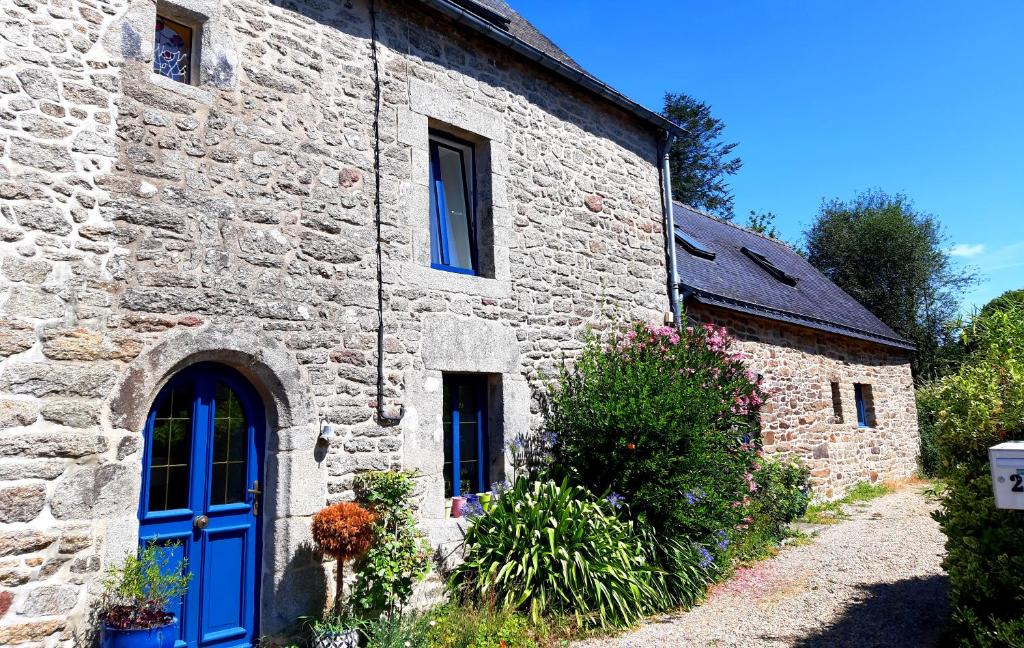 una vecchia casa in pietra con una porta blu di La Maison Douce a Saint-Guyomard